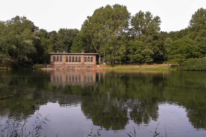 Het bezoekerscentrum is zichtbaar vanaf de waterkant, omgeven door groen en weerspiegeld in het rustige water.