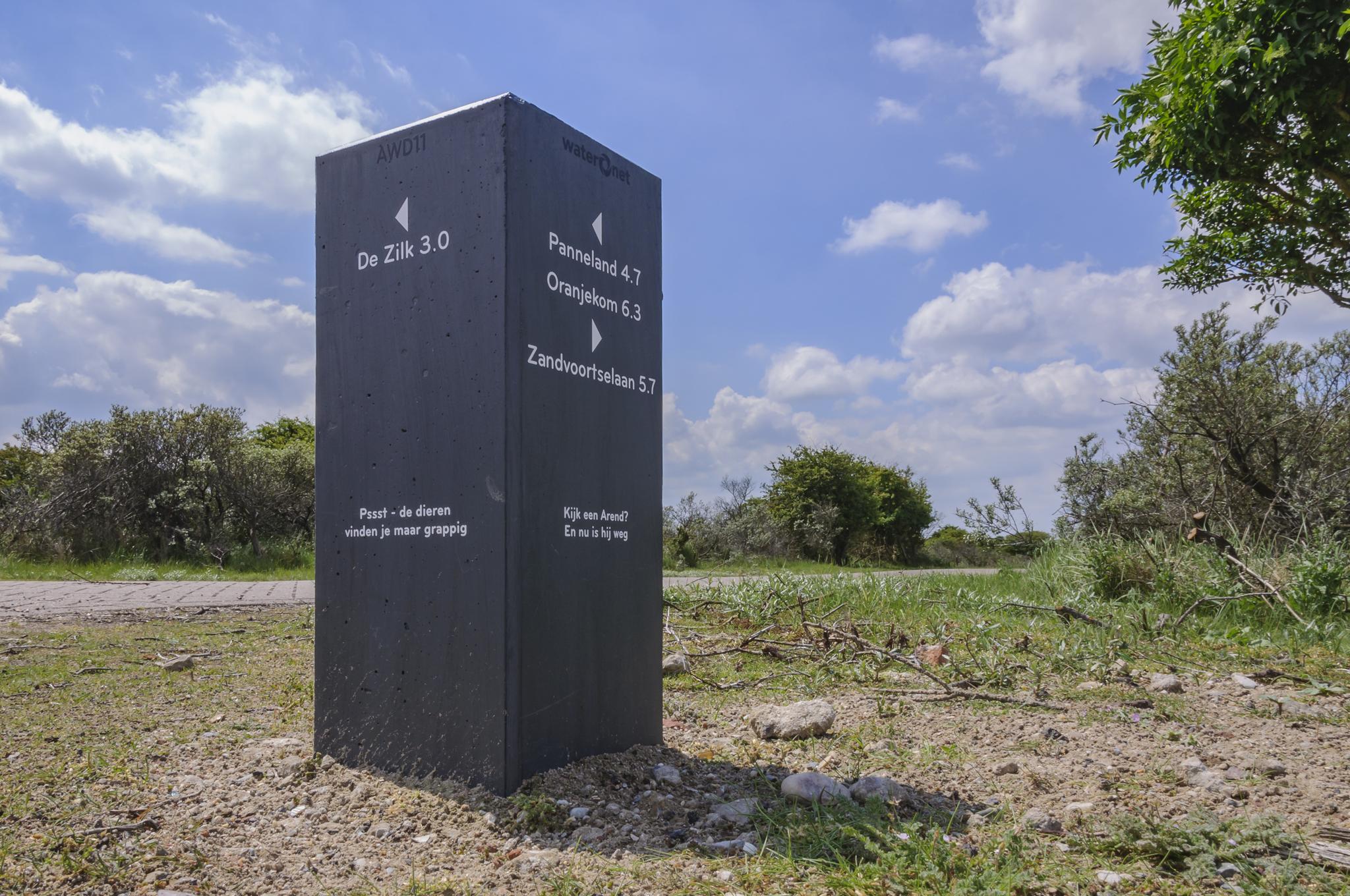 Betonen routepaal met richtingen erop geschreven in kilometers