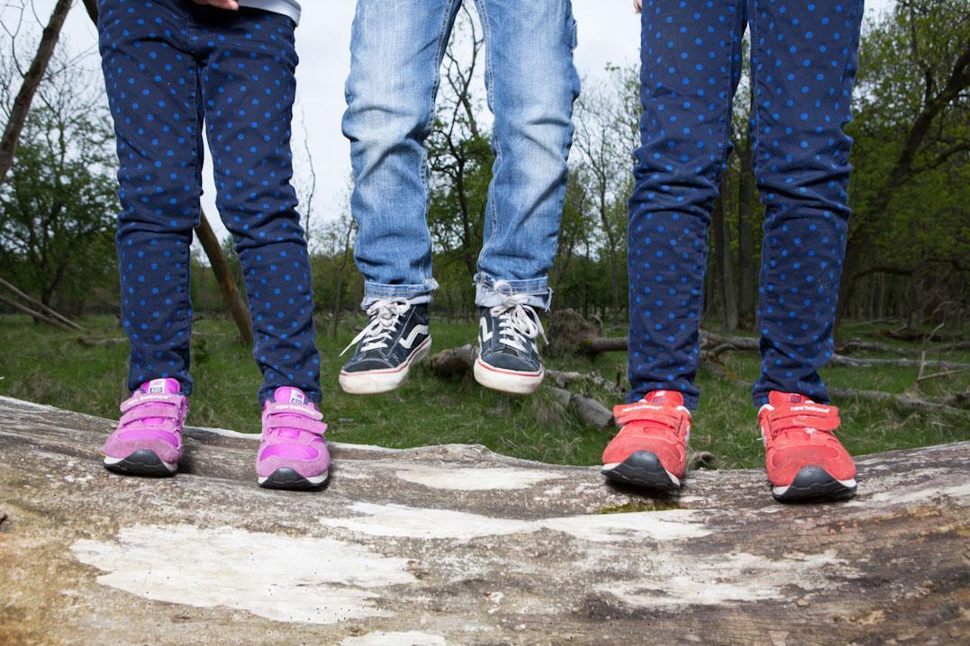 Drie kinderen springen omhoog en alleen de zes benen zijn te zien.