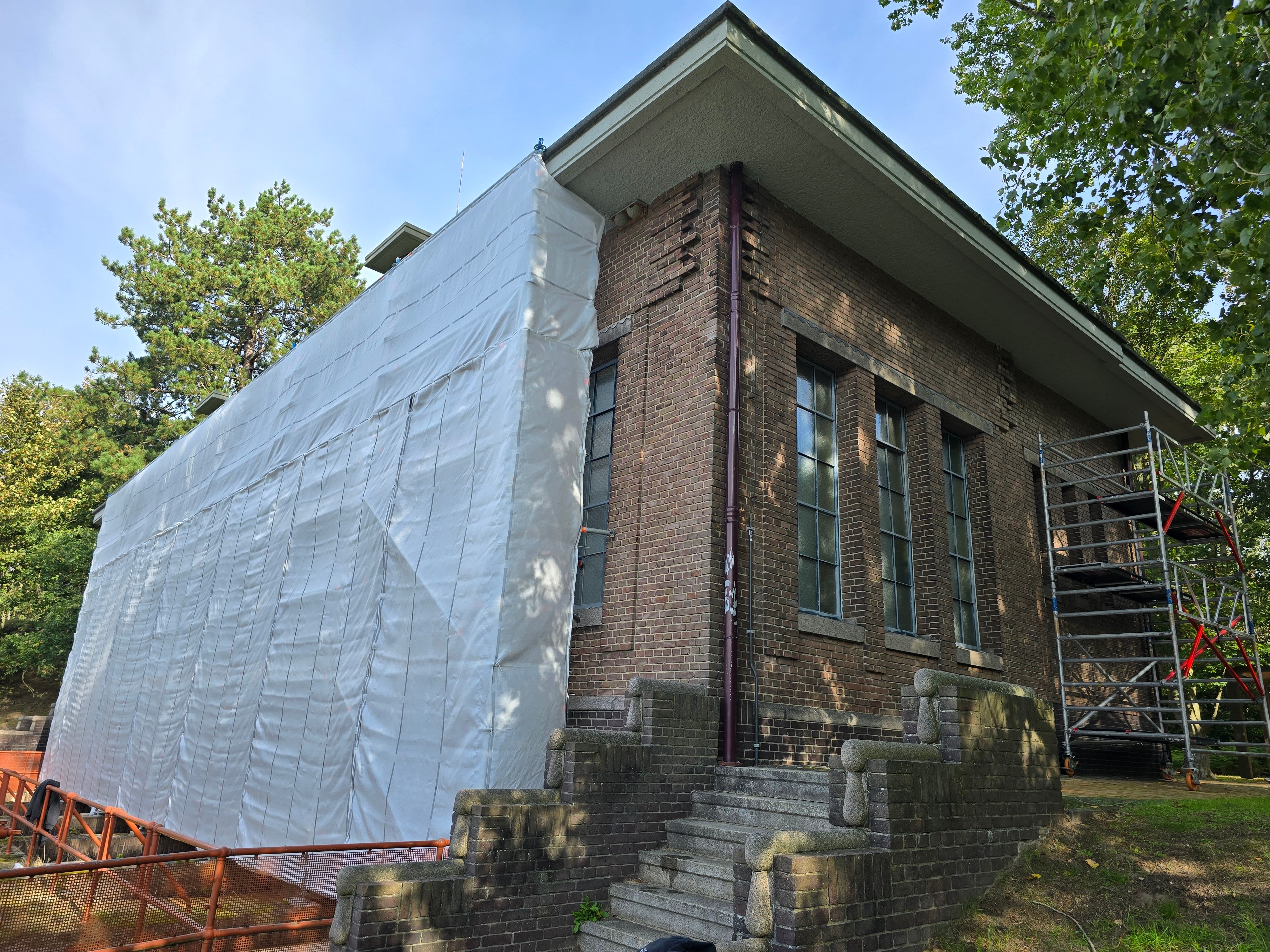 Bezoekerscentrum met daaromheen steigers voor buitenschilderwerk