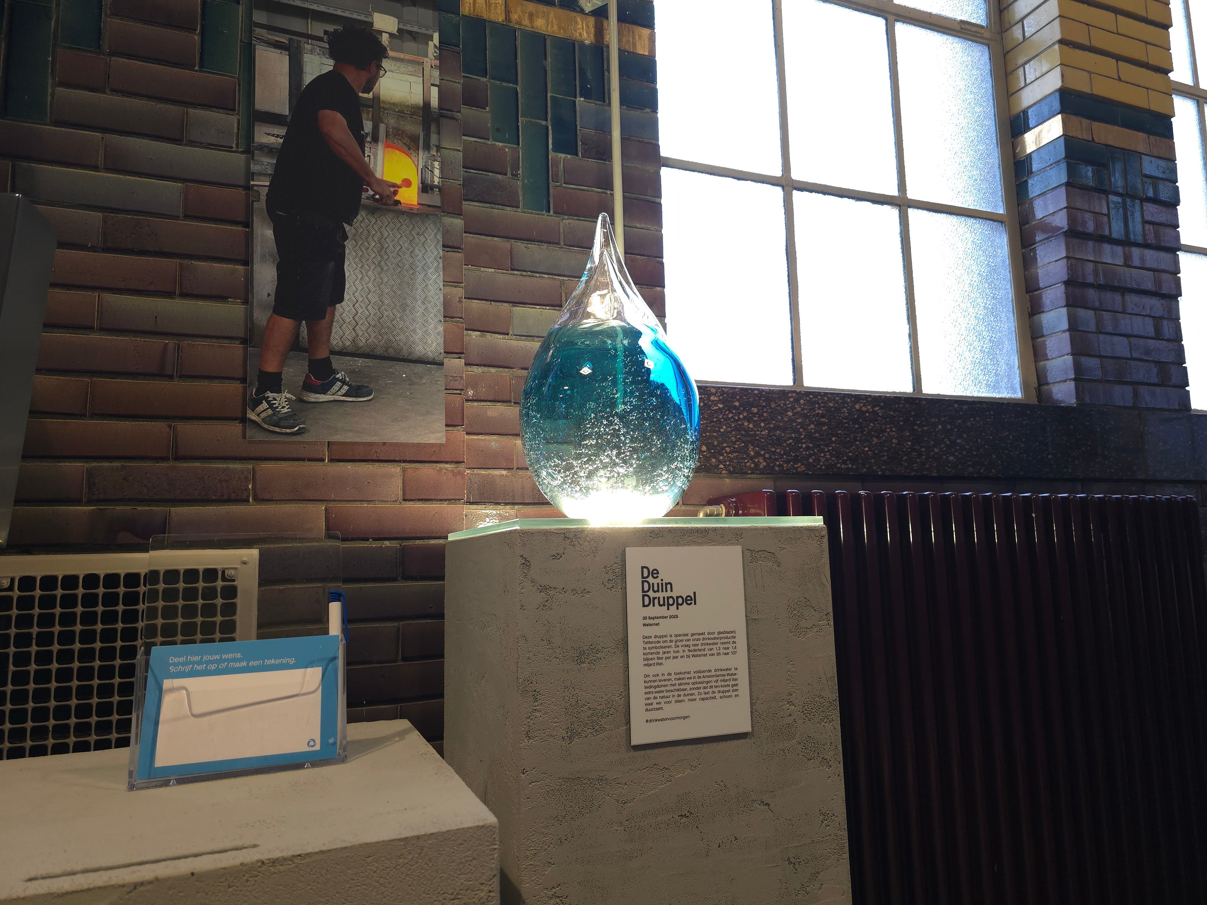 Beeld van een glazen, verlichte drinkwaterdruppel op een sokkel