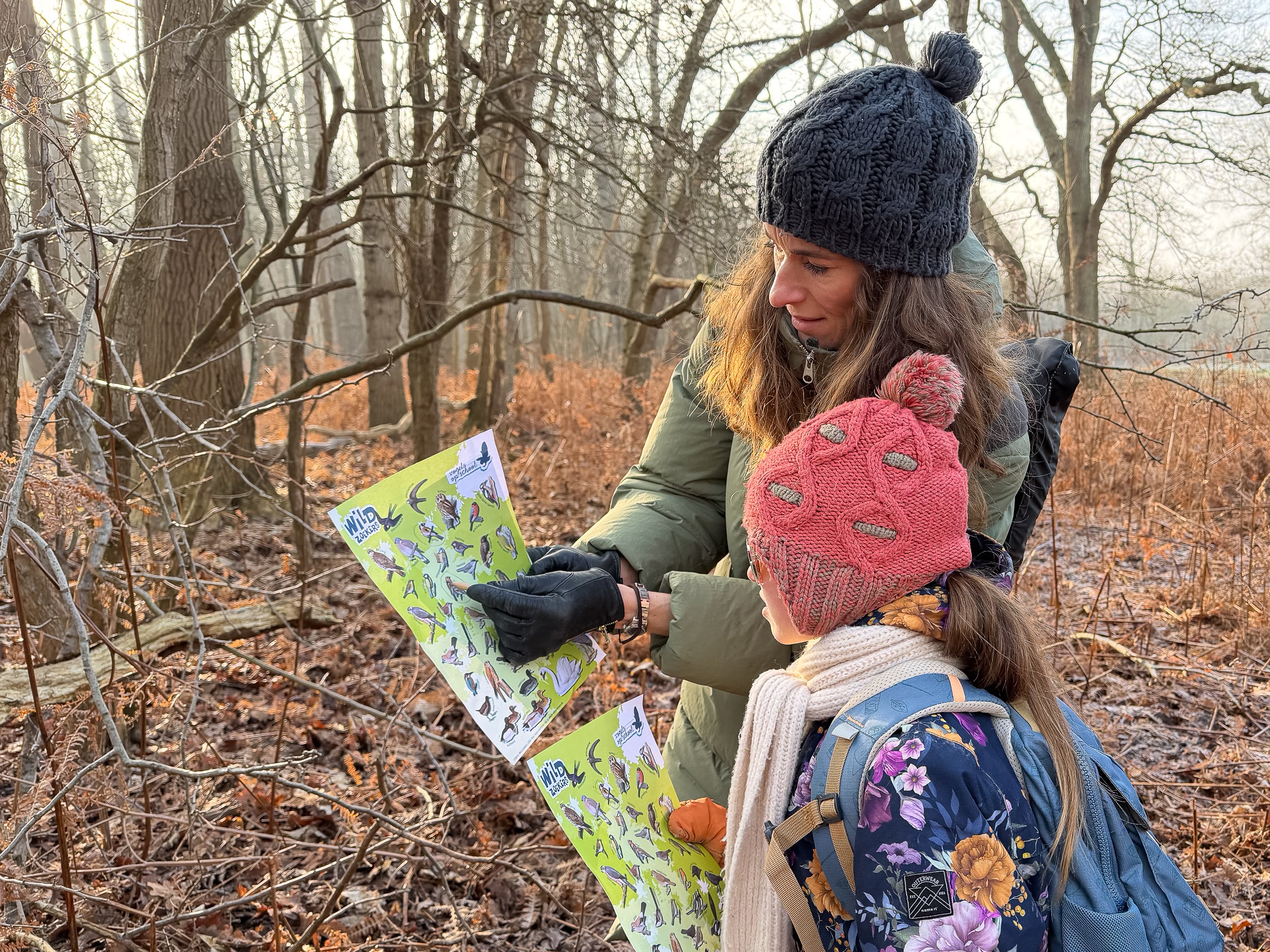 Moeder en kind kijken op een vogelspeurkaart.