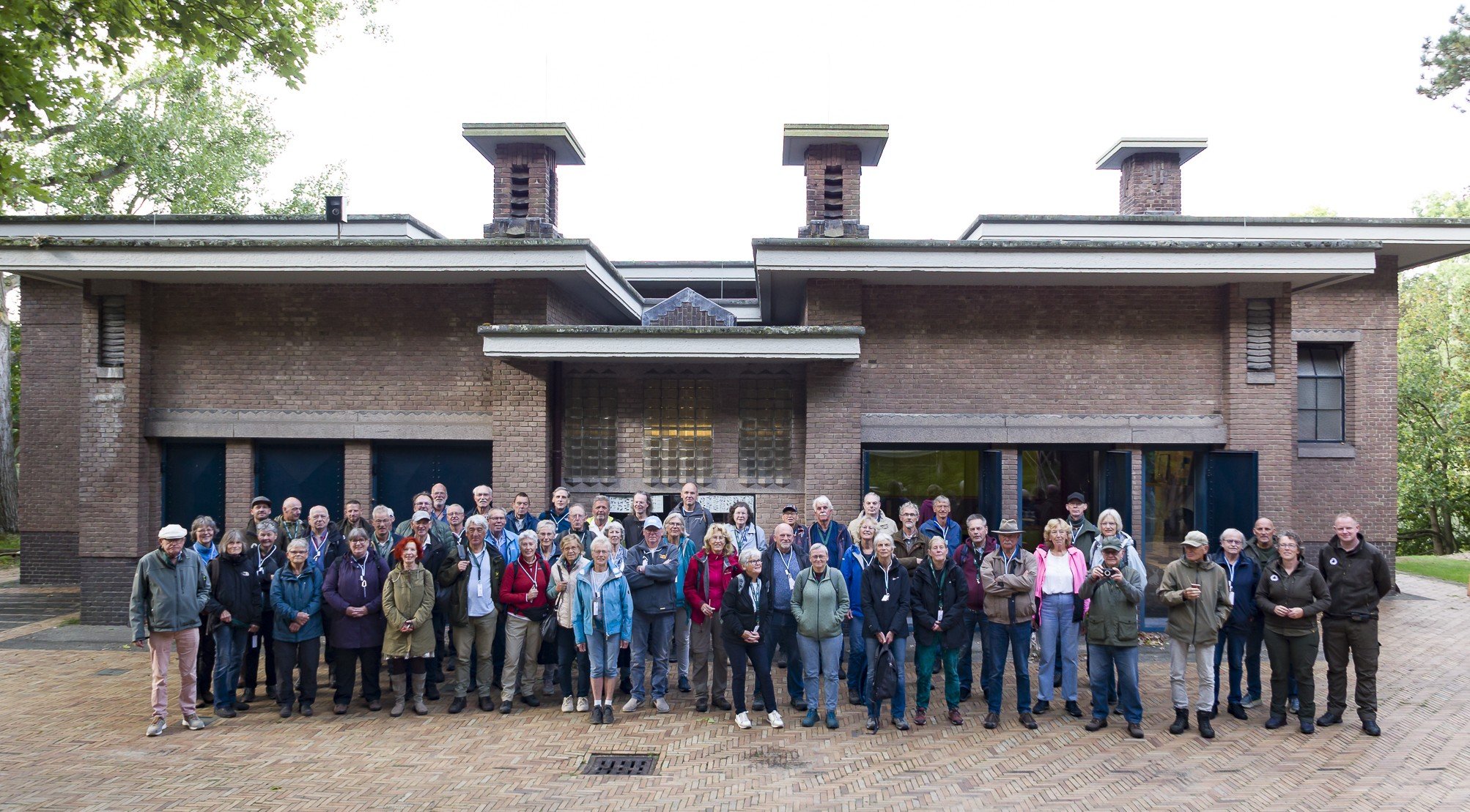 Een groep vrijwilligers staat geposeerd voor het bezoekerscentrum van de AWD