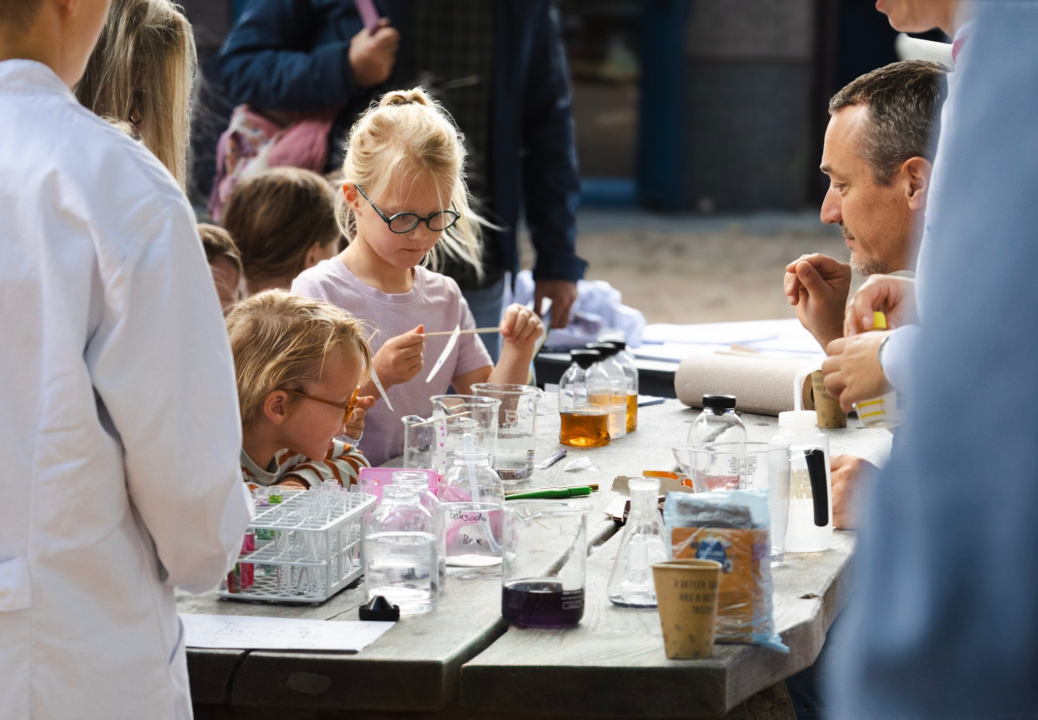 Kinderen en onderzoekers aan een tafel met glazen om waterproefjes mee te doen
